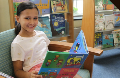 Kid reading a book and smiling. 